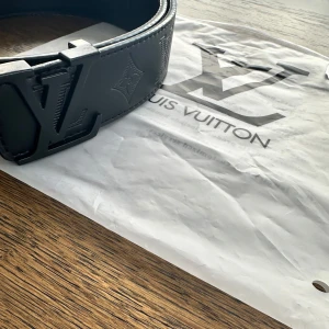 Svart bälte  - Snyggt svart bälte f med präglad logotyp och stilren design. Tillverkat i skinn med en elegant spänne. Perfekt för att ge en lyxig touch till din outfit.