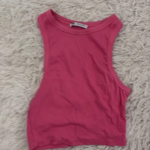 Rosa ärmlös linnetopp - Säljer en snygg rosa ärmlös linnetopp. Perfekt för varma dagar och kan enkelt matchas med olika outfits. Toppen har en enkel och stilren design.