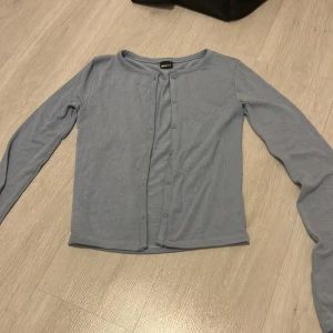 Ljusblå kofta från Weekday - Säljer en stilren ljusblå kofta från gina tricot. Koftan har långa ärmar och knappar framtill. Perfekt för lager-på-lager under kyligare dagar.