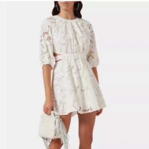 Vit maje klänning i spets med knyt - Säljer en maje klänning som är HELT NY, LAPPEN SITTER KVAR!  Det är en söt vit spetsklänning med trekvartsärm och knyt i ryggen. Klänningen har en öppen rygg och ett fint blommigt mönster. Perfekt för student samt sommarens alla tillfällen!