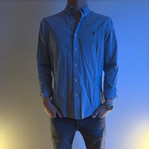 Blårutig skjorta från Ralph Lauren - Snygg blårutig skjorta från Ralph Lauren med klassisk krage och knappar en liten broderad logga på bröstet. Perfekt för en stilren look.