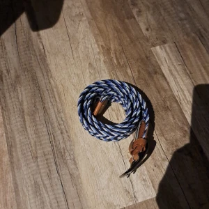 Flätat bälte med läderdetaljer - Snyggt flätat bälte i blått och vitt med bruna läderdetaljer. Bältet har ett klassiskt spänne i metall och passar perfekt för att ge en stilren touch till din outfit. Bältet är helt nytt och är köppt billigt. Jag säljer de för 60kr 