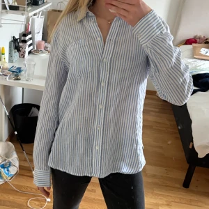 Blå-vit randig linneskjorta - Super snygg och somrig linneskjorta från Hm. Har en lite oversize fit men går att stoppa in om man hellre vill ha det. Köpt på HM och knappt använd så jättebra skick. Pris är diskuterbart, skriv vid frågor eller för fler bilder💗