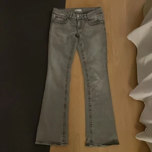 Grå bootcut jeans från Gina Tricot - Snygga grå bootcut jeans från Gina Tricot. De har en klassisk femficksdesign och en knappgylf. Perfekta för en avslappnad stil!