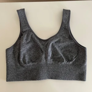 Grå sport-bh M från H&M - Säljer en grå sport-bh i stretchigt material. Den har en ribbad kant nedtill och breda axelband för extra stöd. Perfekt för träning eller en aktiv vardag.