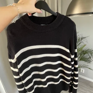 Svart och vit randig tröja från Gina Tricot - Säljer en snygg svart tröja med vita ränder från Gina Tricot. Tröjan har en rund halsringning och långa ärmar, perfekt för en stilren look. Lite norrpig.