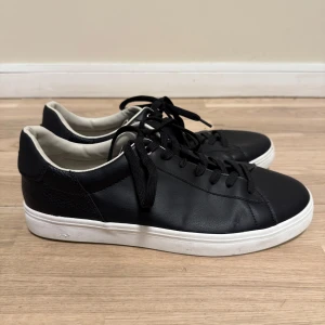 Svarta sneakers från Zara - Snygga svarta sneakers från Zara med vit sula och klassisk snörning. Perfekta för en stilren look. Tillverkade i syntetmaterial för en modern känsla.