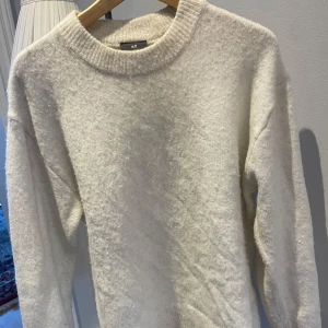 Vit stickad  tröja från H&M - Mysig vit tröja från H&M med relaxed fit. Perfekt för kyliga dagar med sin mjuka och fluffiga textur. Tröjan har långa ärmar och en rund halsringning.