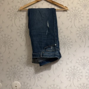 Blå jeans - Snygga blå jeans med en klassisk design. De har en dragkedja och knapp framtill. Sliten jeans modell Perfekta för en avslappnad stil.