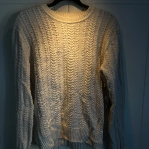 Vit stickad tröja - Säljer en mysig vit stickad tröja med ett klassiskt flätmönster. Mjuk i materialet.