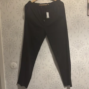 Svarta byxor  - Snygga svarta byxor med dragsko i midjan. Perfekta för en avslappnad stil. Byxorna har en enkel design och är lätta att matcha med olika toppar.