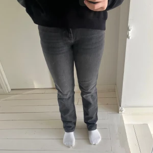 Grå jeansbyxor - Snygga grå jeansbyxor med en klassisk straight passform. De har en normal midja och är perfekta för en stilren look. Byxorna har fem fickor och en dragkedja framtill.