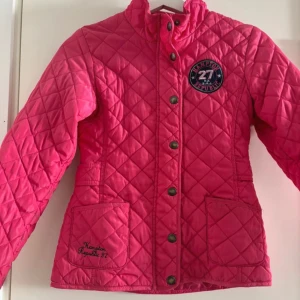 Rosa quiltad jacka från Hampton Republic - Säljer en superfin rosa quiltad jacka från Hampton Republic. Den har en snygg krage och knappar framtill. Perfekt för höst och vår med sina långa ärmar och praktiska fickor. Märket är broderat på fickan och den har en cool badge på bröstet. Passar perfekt för dig som vill ha en stilren och bekväm jacka! Har lite smuts på fickan men går säkert att ta bort, vi har inte försökt. 