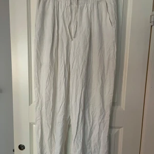 Vita linnebyxor - Säljer ett par vita linnebyxor i loose fit. Perfekta för sommaren med sin lätta och luftiga känsla. Byxorna har en elastisk midja för extra komfort. De är i bra skick och passar både till vardags och festligare tillfällen.