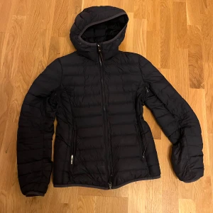 Marinblå dunjacka från Parajumpers juliet  - Säljer en marinblå dunjacka från Parajumpers i storlek S. Jackan är superlätt och har en huva samt dragkedja framtill. Perfekt för kyliga dagar och har en snygg patch på ärmen. Den är i mycket bra skick. 