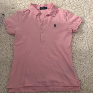 Rosa pikétröja från Ralph Lauren - Säljer en klassisk rosa pikétröja från Ralph Lauren i storlek S. Tröjan har korta ärmar och en broderad logga på bröstet. Perfekt för en avslappnad men stilren look. Passar både till vardags och lite finare tillfällen. knappt använd max 2 gånger bara legat i garderoben. köptes för 1600kr! säljer för ca 700