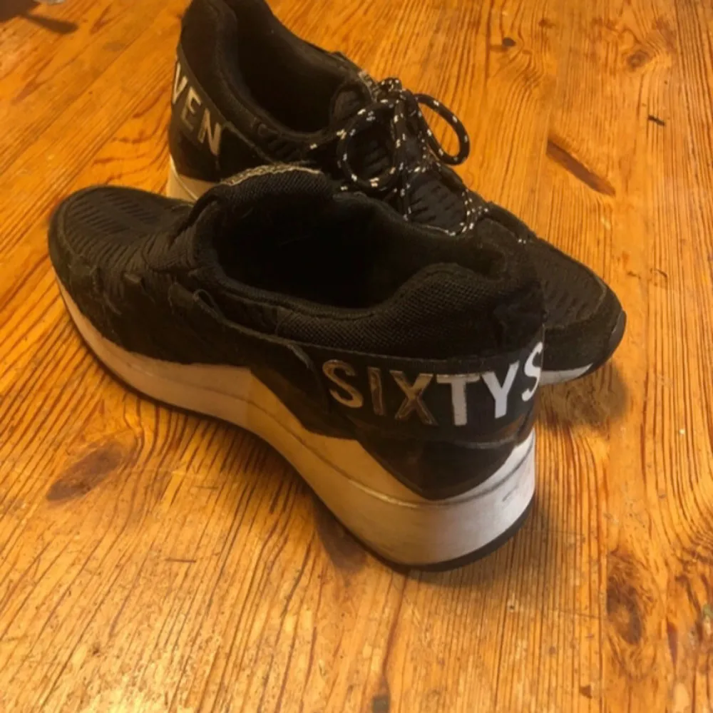 Säljer ett par svarta sneakers från Sixtyseven i bra skick. Skorna har en cool design med vit sula och textdetaljer på hälen. De är gjorda i mocka och textil och har snörning framtill. Perfekta för vardagsbruk eller en avslappnad dag ute. Tyvärr saknas ett snöre och innersulor, men det är lätt att komplettera. Skor.