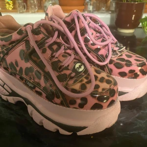 Rosa och svarta sneakers med leopardmönster - Säljer ett par coola Buffalo sneakers i rosa och svart med leopardmönster. De har en chunky sula och rosa snörning som ger en unik look. Perfekta för att sticka ut i mängden! 🐆