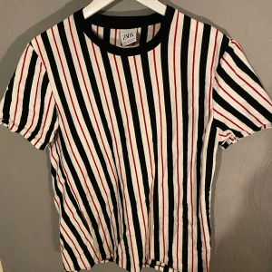 Randig t-shirt från Zara - Säljer en snygg randig t-shirt från Zara i svart, vit och röd. Den har en klassisk rund hals och korta ärmar, perfekt för vardagsbruk. Materialet känns mjukt och bekvämt, idealiskt för både sommar och vår. Passar bra till jeans eller shorts! (PM OM DU VILL HA FLER BILDER)