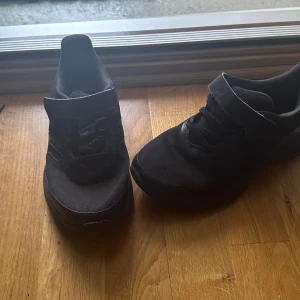 Svarta sneakers med snörning - Säljer ett par svarta sneakers i mycket bra skick. De har en stilren design med snörning och en bekväm passform. Perfekta för vardagsbruk eller träning. Skorna är i syntetmaterial och har en diskret look som passar till det mesta.