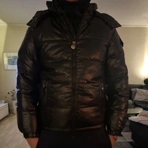 Svart pufferjacka - Säljer en snygg svart pufferjacka i mycket bra skick. Jackan har en dragkedja framtill och är perfekt för kalla dagar. Den är långärmad och har en hög krage för extra värme. Passar perfekt för vintern och hösten!