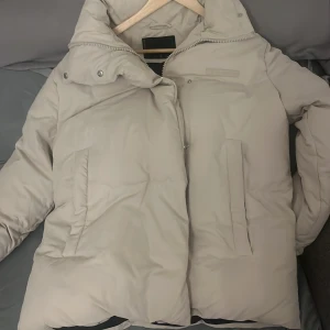 Beige pufferjacka från FB Sister - Säljer en snygg beige pufferjacka från FB Sister i storlek S. Jackan har en dragkedja och knappar framtill, perfekt för kalla vinterdagar. Den är i mycket bra skick och supermysig att ha på sig. Passar perfekt till både vardag och fest! 🧥✨