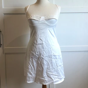 Vit klänning - Säljer en söt vit klänning med spetsdetaljer och smala axelband. Klänningen har en lätt och luftig känsla, perfekt för varma sommardagar. Kan också användas som en underklänning. Köpt i en liten butik i Seoul. Aldrig använd! Säljer då den inte är min stil. 