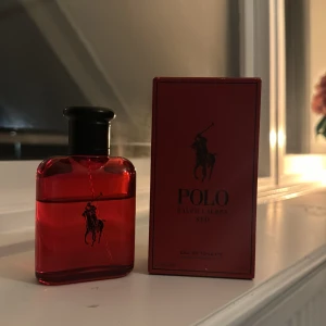 Röd parfym från Ralph Lauren - Säljer en snygg röd parfymflaska från Ralph Lauren. Flaskan har en stilren design med en svart kork och den ikoniska Polo-loggan. Perfekt för den som vill ha en fräsch och maskulin doft. Passar både till vardags och fest. Flaskan är i gott skick och redo att användas. Perfekt presentidé eller för att unna sig själv något extra! 🌟(OBS! PARFYMEN ÄR LITE ANVÄND)
