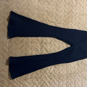 Svarta ribbade byxor - Säljer ett par svarta ribbade byxor i mycket bra skick. De har en skön och stretchig passform som är perfekt för både vardag och fest. Byxorna har en bootcut-stil som ger en snygg siluett. Perfekta för höst och vinter!