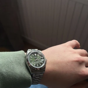 Seiko klocka med grön urtavla - Säljer en snygg Seiko klocka med en grön urtavla och datumvisning. Klockan har ett automatiskt urverk och ett stilrent silverfärgat armband i metall. Säljer för en billigare peng då ja köpt en annan