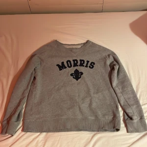 Grå sweatshirt från Morris - Säljer en snygg grå sweatshirt från Morris i mycket bra skick. Den har ett tryck med Morris-loggan i svart på bröstet. Tröjan är långärmad och perfekt för både höst och vår. Superbekväm och stilren, passar till det mesta i garderoben!