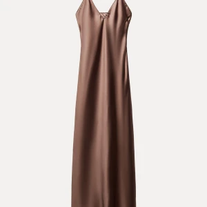 Brun långklänning i satin - Elegant brun långklänning i satin med en v-ringad design. Perfekt för festliga tillfällen med sin släta och glänsande yta. Klänningen har en enkel och stilren look som passar både till nyår och andra speciella tillfällen.