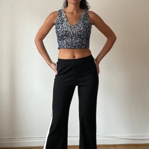 Glittrig croppad topp - Säljer en superfin glittrig croppad topp i silver. Perfekt för festliga tillfällen! Toppen är ärmlös och har en djup v-ringning. Den är både bekväm och stilren, perfekt för att sticka ut på festen. Passar bra till både byxor och kjol.