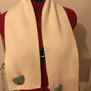 Vit stickad halsduk med dekorativa detaljer - Superfin vit stickad halsduk med söta dekorativa detaljer i form av små blommor i blått och rosa. Perfekt för att hålla sig varm under kyliga dagar. Den är mjuk och bekväm, vilket gör den idealisk för både vardag och festliga tillfällen. Ett måste för vinterns garderob! Använd köp nu eller Swish. Kan mötas upp i Helsingborg 