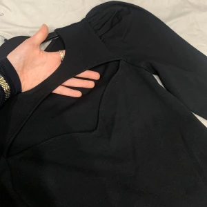 Svart långärmad bodysuit - Snygg svart body med långa ärmar och puffiga axlar. Den har ett annorlunda material nästan som träningskläder men ändå inte då tyget är lite tjockare. Den formar midjan väldigt fint och drar åt kroppen om man säger så. Fin att ha till tjejkvällar då den kanske är lite väl för öppen...🙃