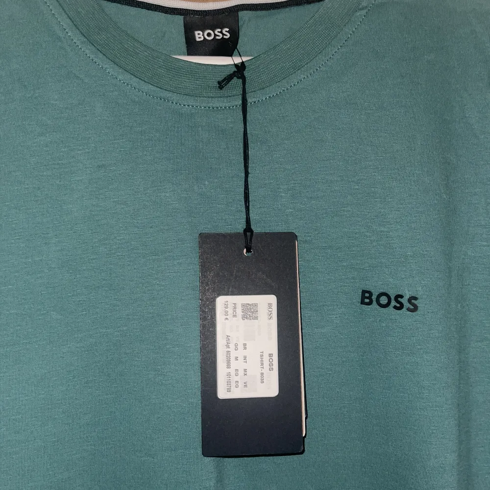 Säljer en snygg grön t-shirt från BOSS i nytt skick. Den är kortärmad och har en stilren design med BOSS-loggan på bröstet. Perfekt för både vardag och fest! 💚. T-shirts.