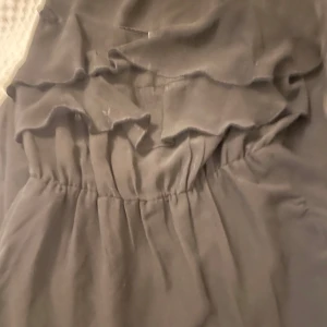 Svart klänning från Bik Bok - Snygg svart klänning från Bik Bok i storlek XS. Den har volangdetaljer och en elastisk midja för en bekväm passform. Perfekt för festliga tillfällen eller en utekväll. Klänningen är i mycket bra skick och redo att bäras!
