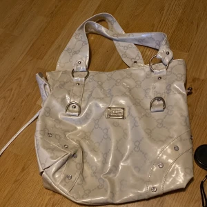 Y2k liknande väska🫶🏻 - Jättefin, inga synliga skador och precis som ny! Köpt på vinted, vet inte direkt vilken färg men mest vit. Jättemycket utrymme och 2 småpfack för småsaker i, skriv för fler frågor🫶🏻 Bredd: 35cm Längd: 31cm Band: ungefär 46cm