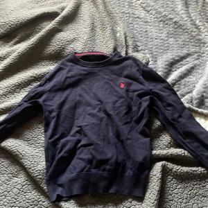 Mörkblå tröja från Ralph Lauren - Säljer en snygg mörkblå tröja från Ralph Lauren med deras ikoniska röda logga på bröstet. Tröjan är långärmad och perfekt för både höst och vinter. Den har en klassisk passform och är superbekväm. Perfekt för en stilren look!