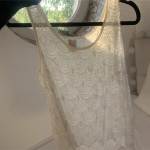 Vit pärlbroderad topp från Vila - Säljer en superfin vit topp från Vila i storlek XS. Den är ärmlös och har ett vackert pärlbroderat mönster som ger en elegant touch. Perfekt för sommarens fester eller en stilren vardagslook. Toppen är i nyskick och redo för nya äventyr! ✨