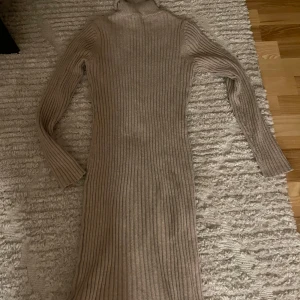 Beige ribbad klänning - Säljer en superfin beige ribbad klänning med polokrage. Den är långärmad och perfekt för höst och vinter. Klänningen är i ett mjukt och stretchigt material som sitter bekvämt på kroppen. Perfekt för en mysig dag eller en stilren look. 🧥✨