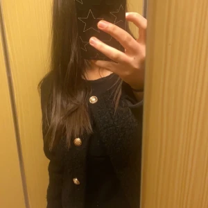 Svart kofta/kappa med guldknappar - Säljer en snygg svart kavaj med guldknappar. Perfekt för både vardag och fest! Den har en normal passform och långa ärmar. Kavajen är i mycket bra skick och ger en stilren look. Ingår med frakt . Passar både M och S