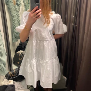 Vit klänning med öppen rygg - Säljer en superfin vit klänning med puffiga ärmar och en söt öppen ryggdetalj. Den har en knytning i ryggen och är perfekt för sommarens alla fester. 