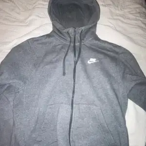 Säljer en grå hoodie från Nike i storlek S passar M. Den har en dragkedja framtill och en justerbar huva med snören. Perfekt för både träning och vardag. Hoodien är i mycket bra skick och superbekväm att ha på sig. Passar perfekt till höst och vår!