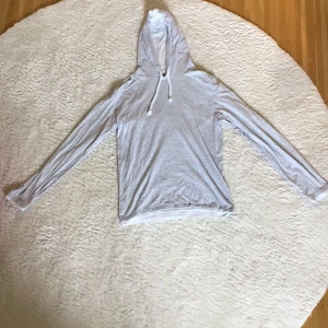 Grå slim fit hoodie - Säljer en ljusgrå, tunn hoodie. Perfekt när det är för varmt för en tjock hoodie. Den har vita snören med dragsko i luvan. 