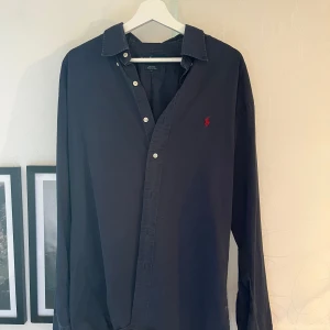 Ralph lauren skjorta  - Säljer min mörkblå ralph lauren skjorta då den är lite stor. Den är i fint skick!  Storlek M men sitter lite större så passar även L