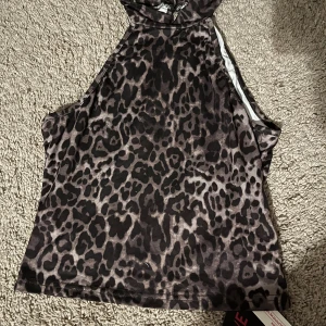 Leopardmönstrad ärmlös topp - Säljer en snygg leopardmönstrad topp som är ärmlös och perfekt för en utekväll. Den har en tight passform och är gjord i ett mjukt och stretchigt material. Toppen är i nyskick och redo att bäras till nästa fest!