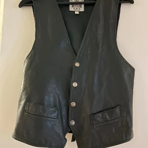genuin 70-tals läder väst - genuin vintage läder imitations väst. bra men användt skick, bilder går att få. unika stjärn knappar och justerbar i ryggen 🙌 mindre i storleken