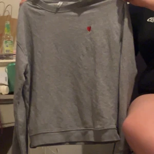 Grå sweatshirt med rött hjärta - Säljer en grå sweatshirt med ett litet rött hjärta på bröstet. Tröjan har långa ärmar och en rund halsringning. Perfekt för en avslappnad stil. Hör av dig vid intresse! 💌