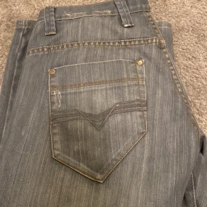Grå/blå jeansbyxor - Dessa blå/grå baggy jeans kombinerar stil och komfort med en avslappnad passform. De har klassiska detaljer och passar perfekt för både vardag och fest. Ett måste i garderoben!
